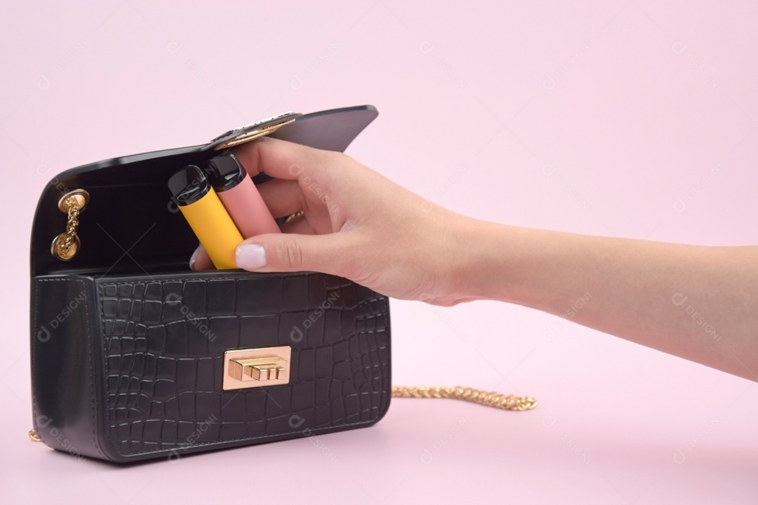 Mulher guardando cigarro eletrônico dentro de bolsa preta