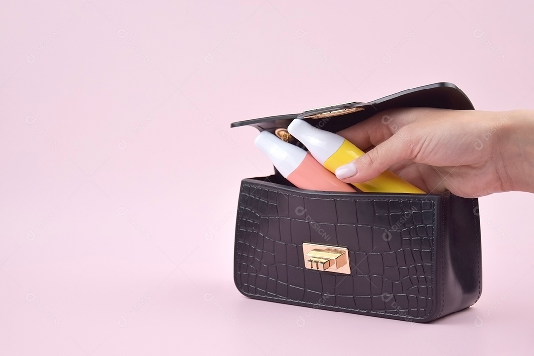 Bolsa preta e mão de mulher guardando cigarro eletrônico sobre fundo claro