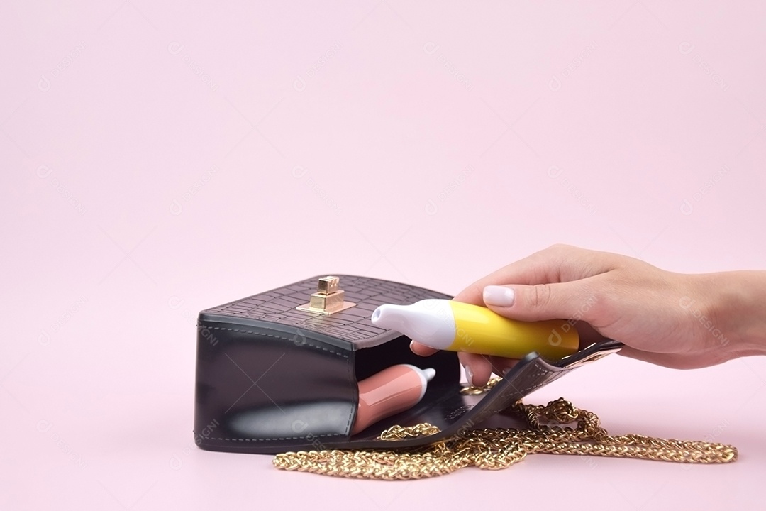 Bolsa preta e três cigarros eletrônicos colorido sobre fundo rosa claro