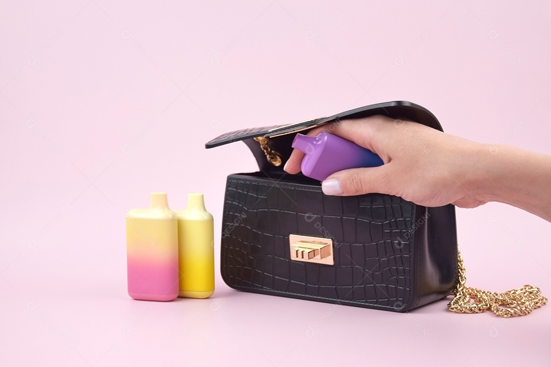 Cigarro eletrônico coloridos e mão colocando outro dentro da bolsa sobre fundo claro