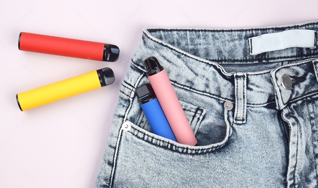 Vários cigarros eletrônicos descartáveis ​​multicoloridos em bolso de jeans