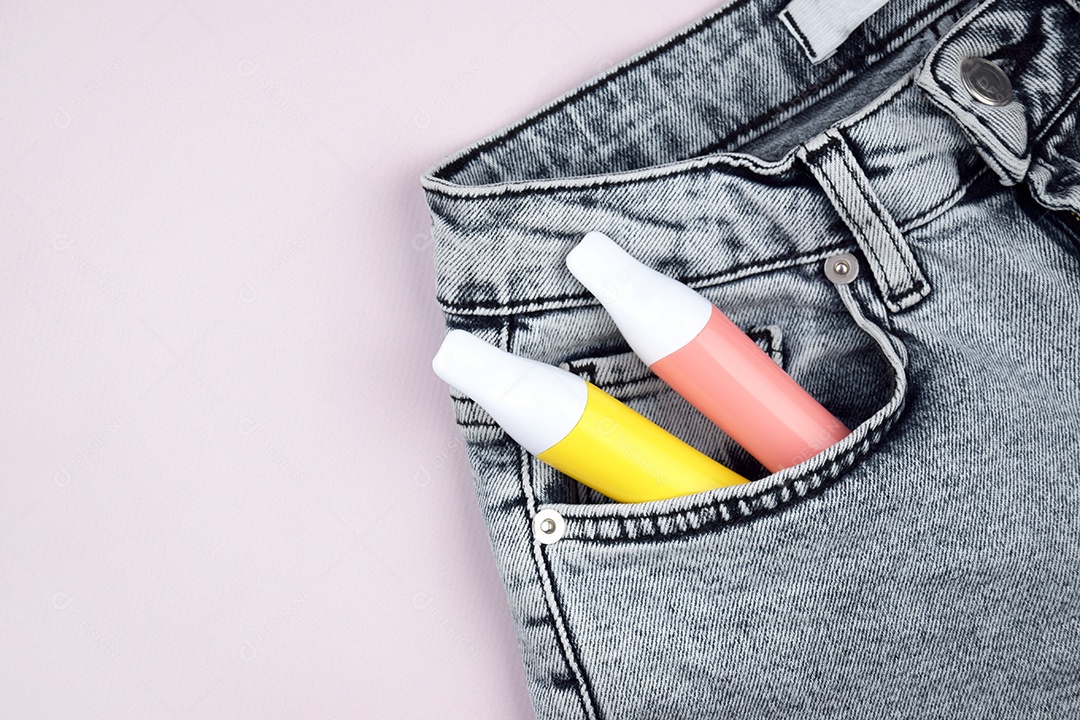 Cigarro eletrônico coloridos em bolso de jeans sobre fundo claro