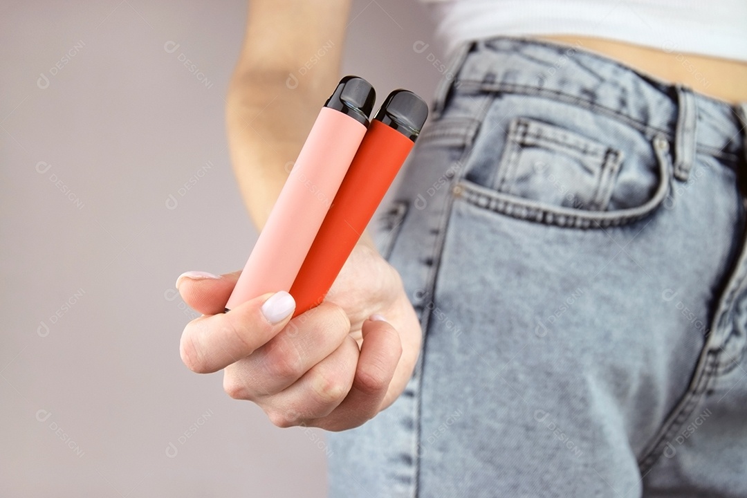 Mulher com cigarros eletrônicos em bolso de jeans sobre fundo claro