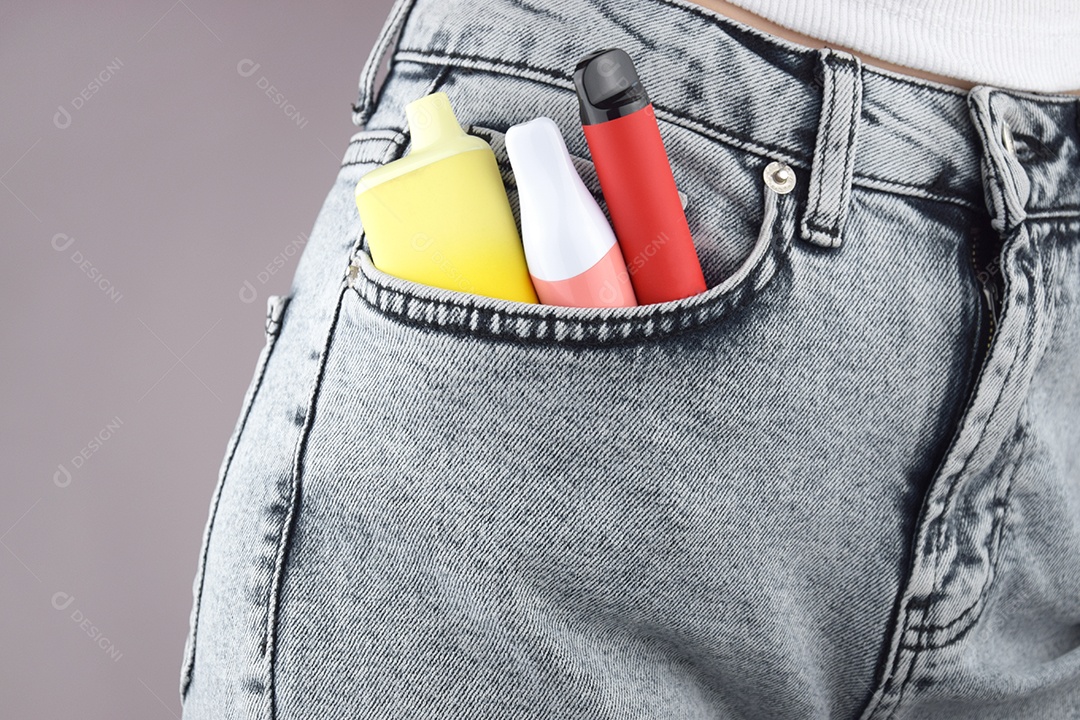 Cigarro eletrônico coloridos em bolso de jeans sobre fundo claro