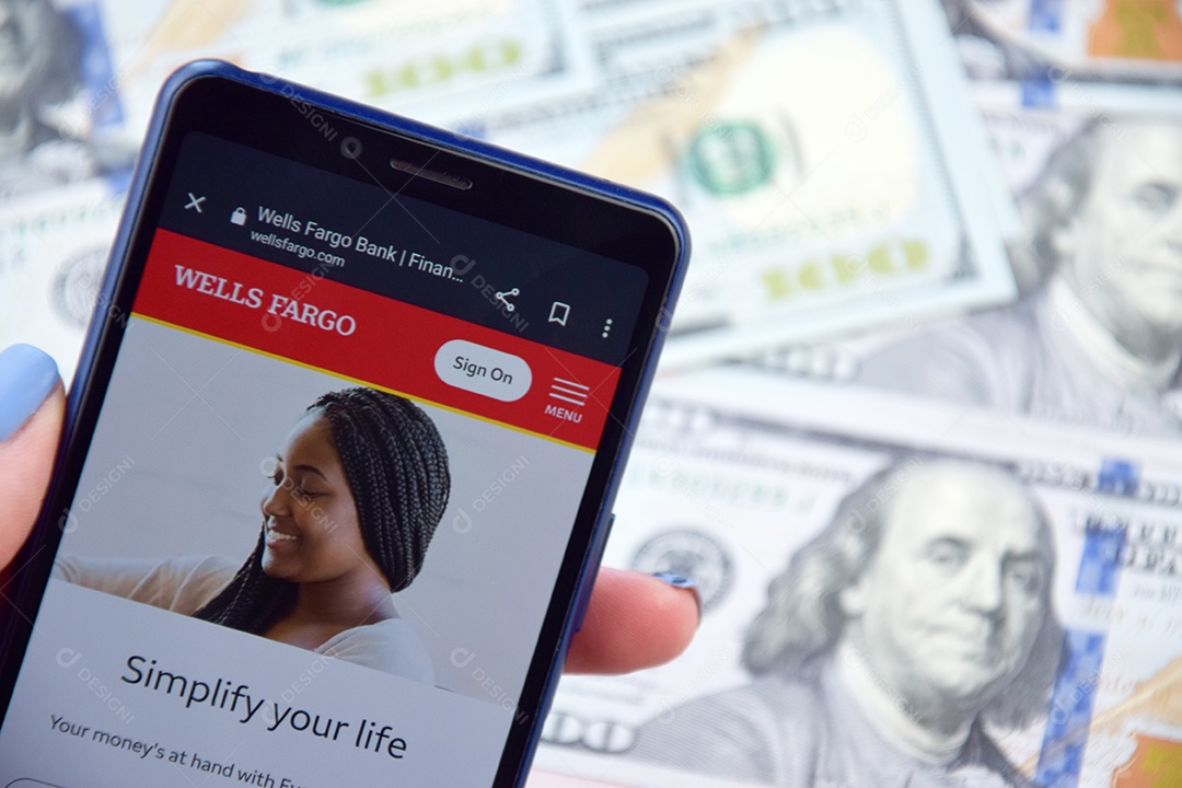 Aplicativo de banco móvel Wells Fargo na tela do celular sobre notas de dólar americano