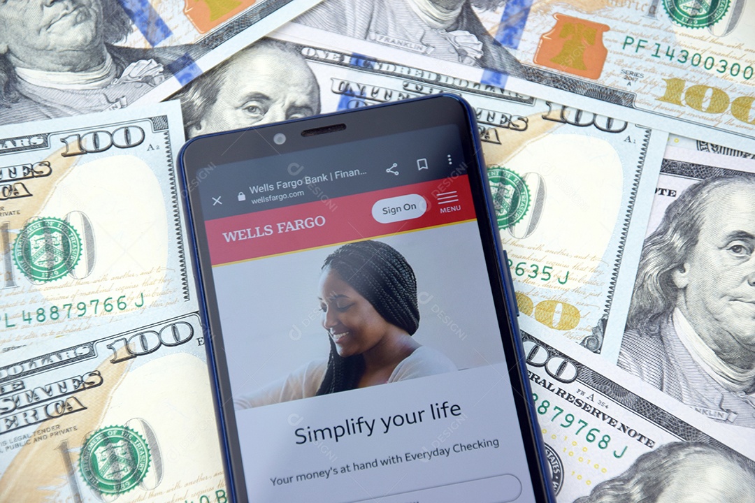 Aplicativo de banco móvel Wells Fargo na tela do celular sobre notas de dólar americano