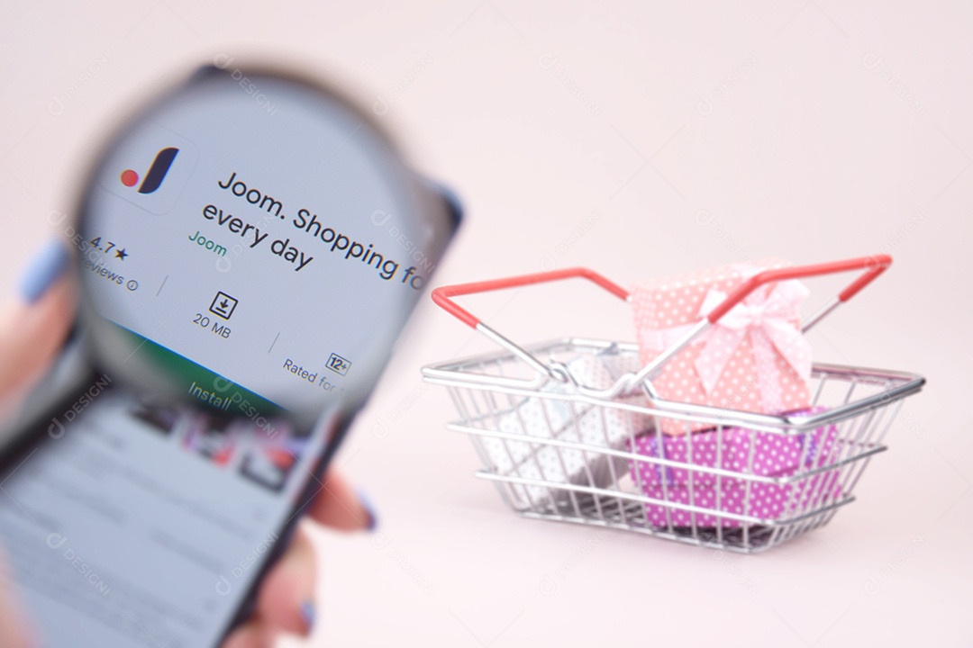 Carrinho de compras com um smartphone abriu o logotipo do Joom na tela em um fundo rosa
