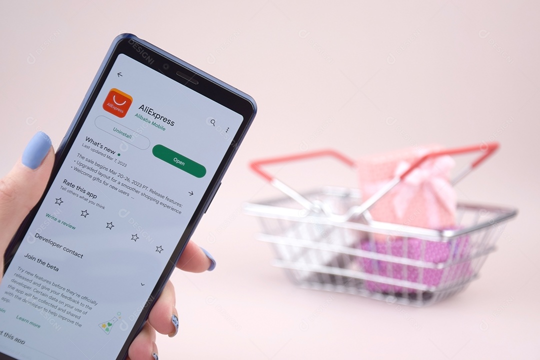 Cesta de compras com smartphone abriu o logotipo do Aliexpress na tela em um fundo rosa