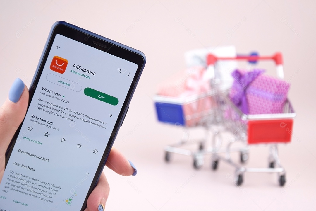 Carros de compras um smartphone com logotipo do Aliexpress na tela sobre fundo rosa