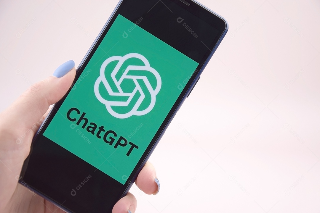 Mão feminina segura o telefone com o logotipo Chat GPT contra o fundo da tela do monitor