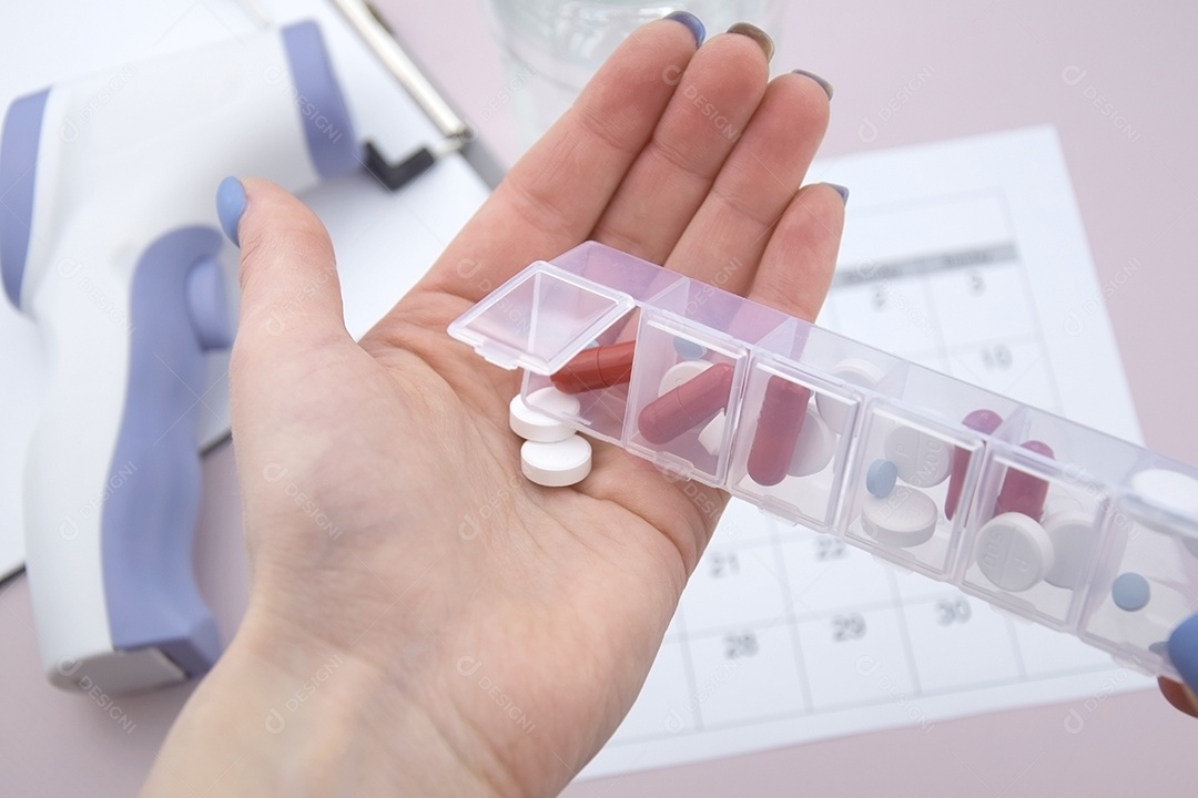Porta comprimidos e mão feminina colocando remédios