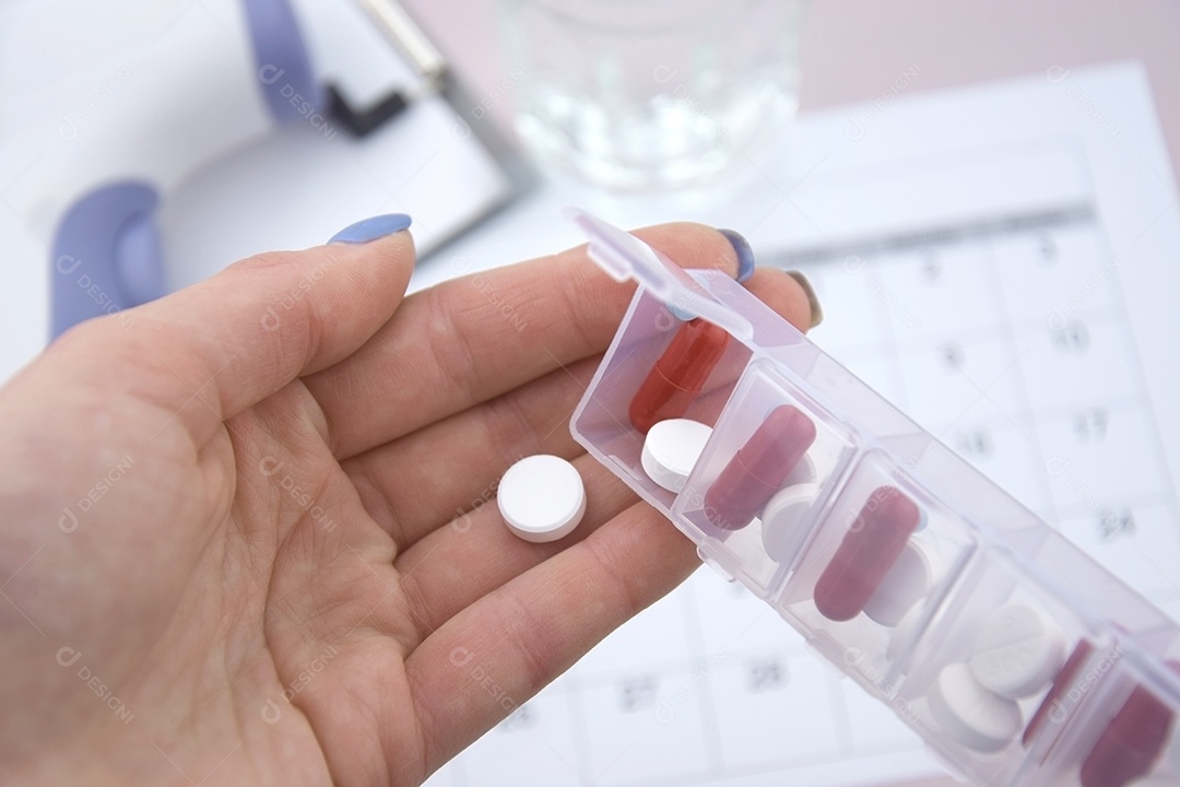 Porta remédios e mão pegando medicamentos