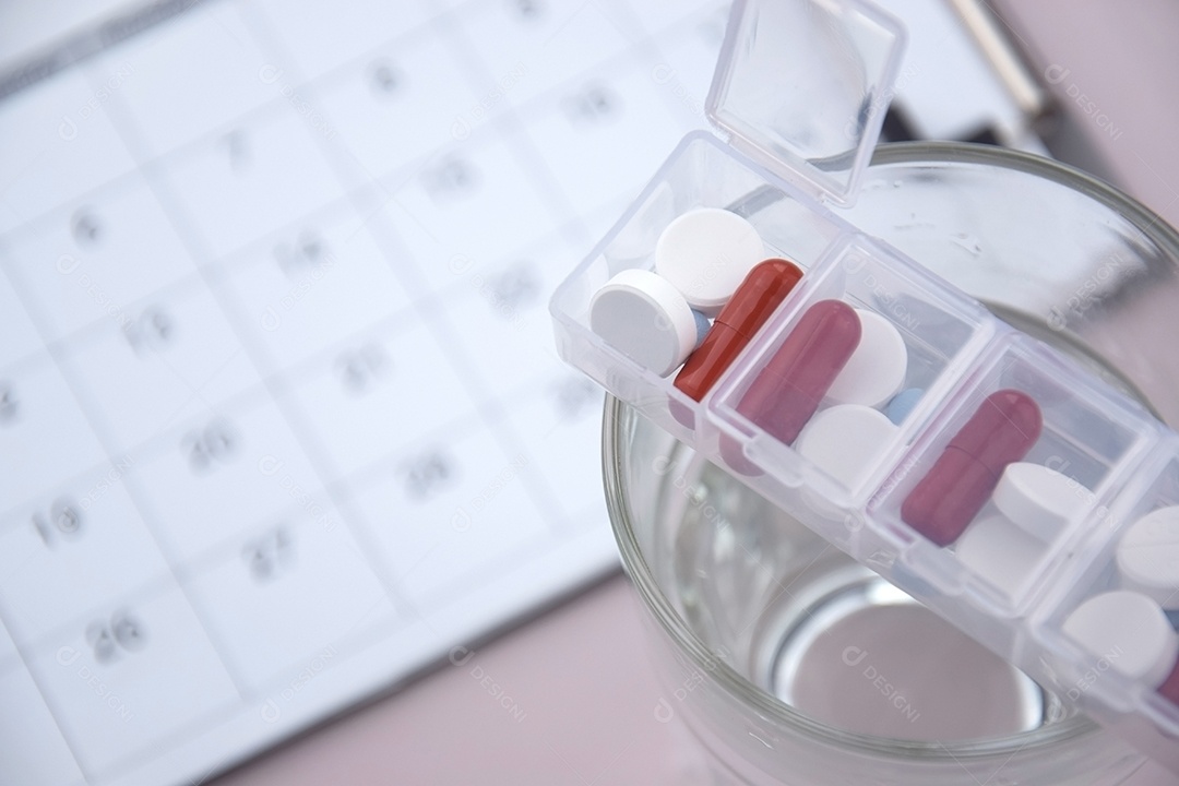 Copo com porta remédios em cima e calendário de fundo