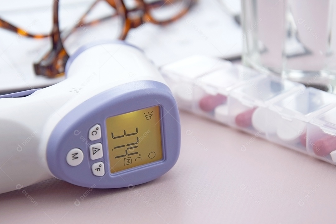 Termômetro e comprimidos óculos e copo sobre fundo claro