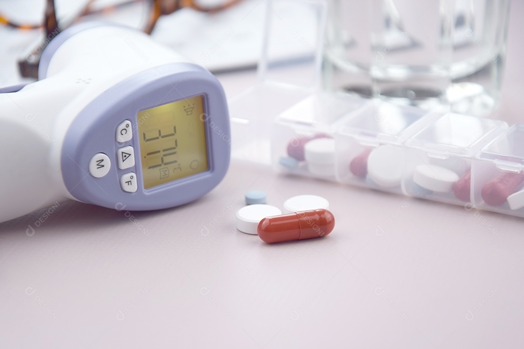 Termômetro e comprimidos sobre fundo claro