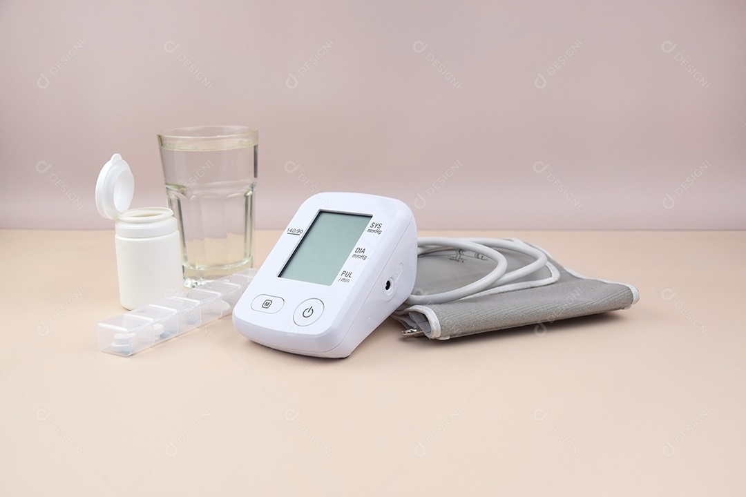 Aparelho digital de pressão arterial copo e comprimidos em um fundo claro