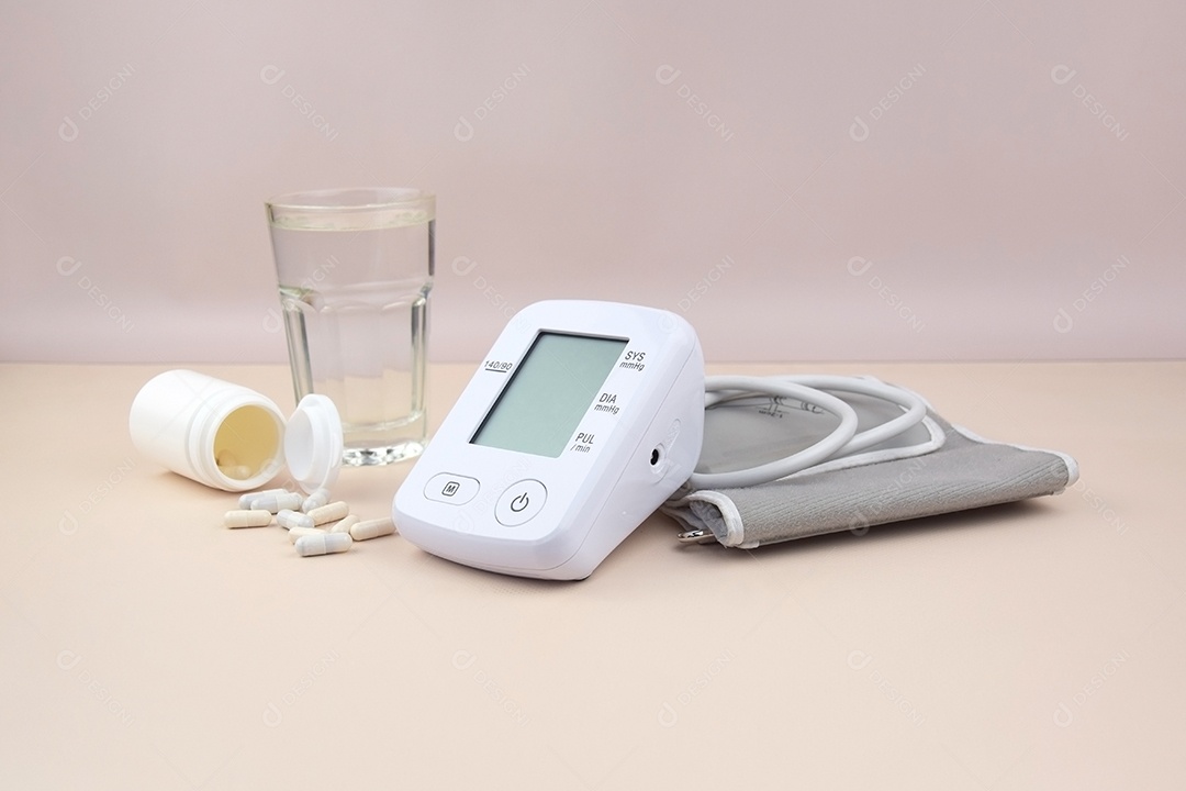 Aparelho digital de pressão arterial copo e comprimidos em um fundo claro