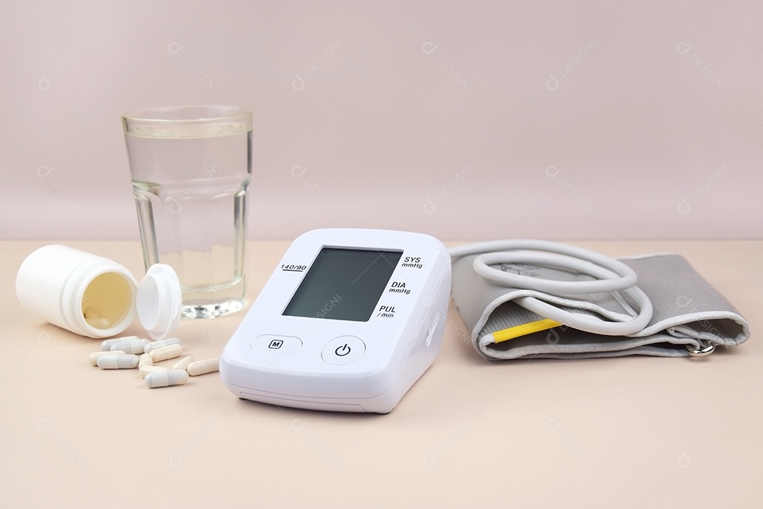 Aparelho digital de pressão arterial copo e comprimidos em um fundo claro