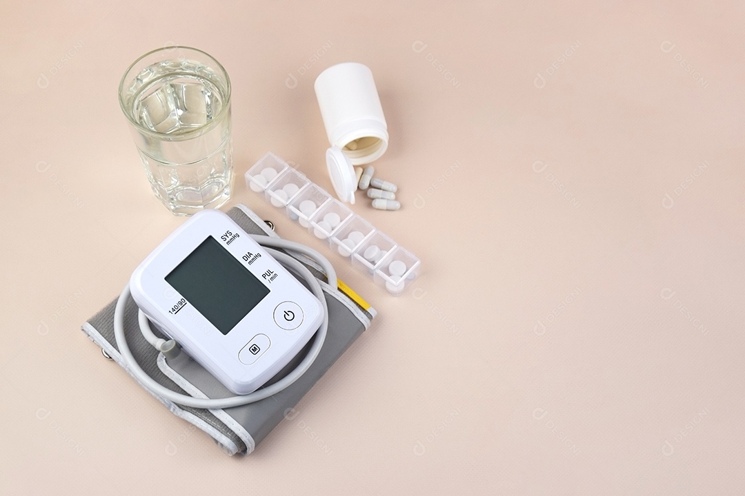 Aparelho digital de pressão arterial e pacote de comprimidos em um fundo claro