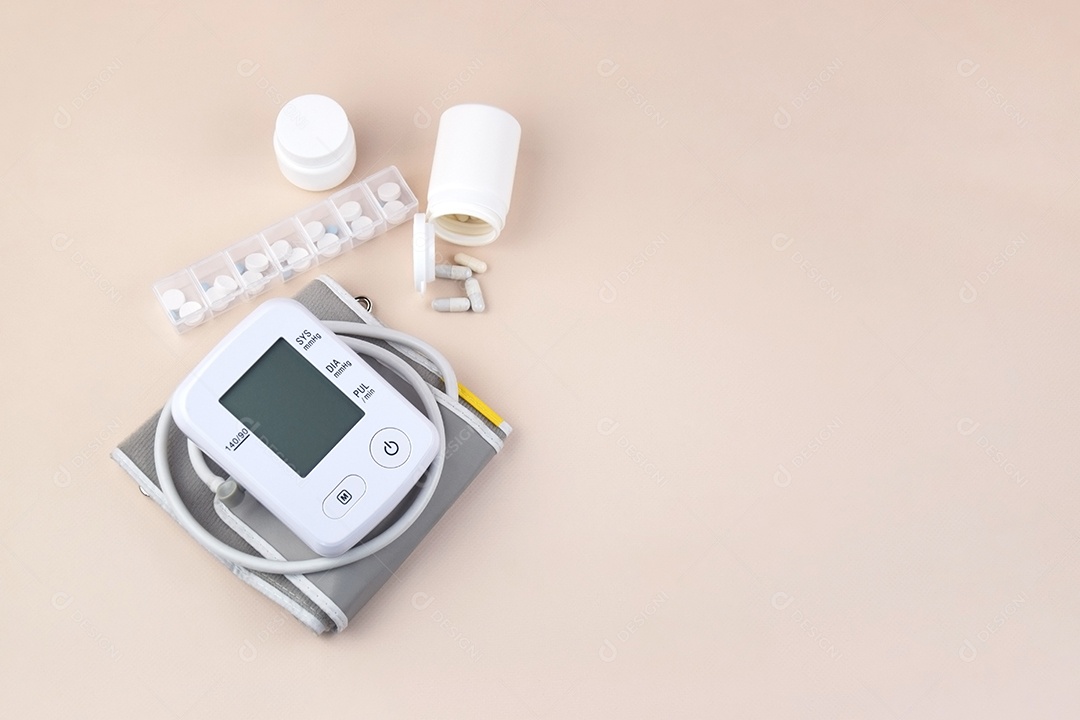 Aparelho digital de pressão arterial e pote de comprimidos em um fundo claro