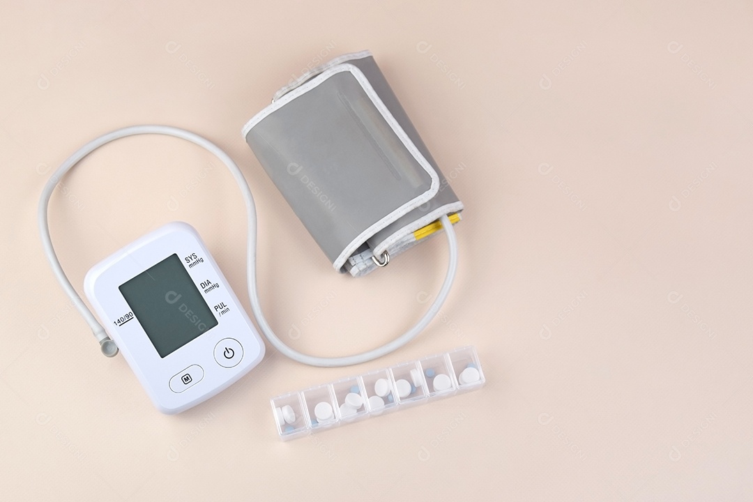 Aparelho digital de pressão arterial e porta de comprimidos em um fundo claro