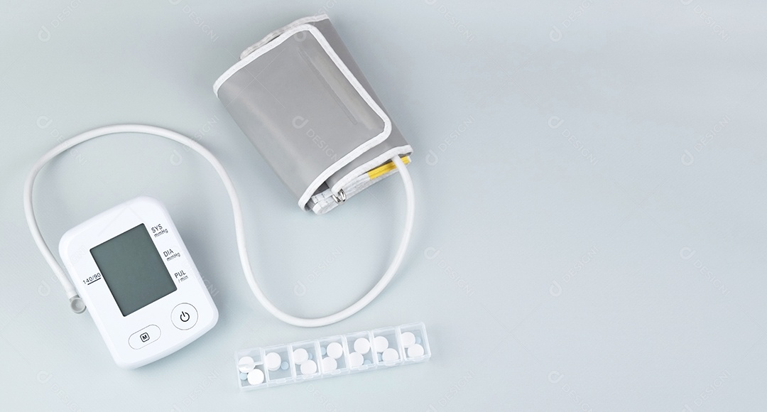 Aparelho digital de pressão arterial e porta comprimidos em um fundo claro