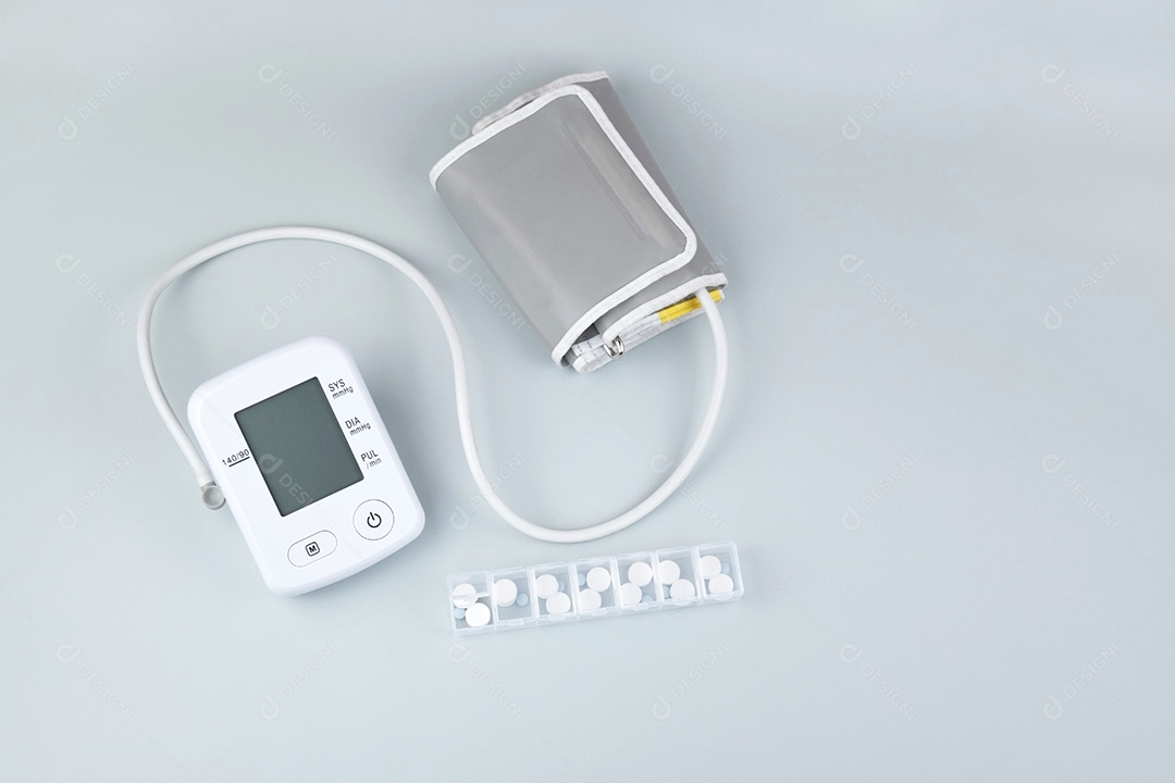 Aparelho digital de pressão arterial e comprimidos em um fundo claro