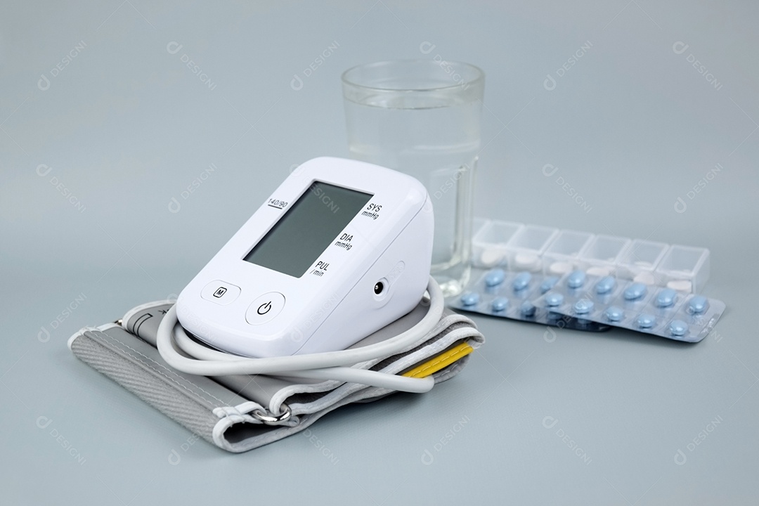 Aparelho digital de pressão arterial e pacote de comprimidos em um fundo claro