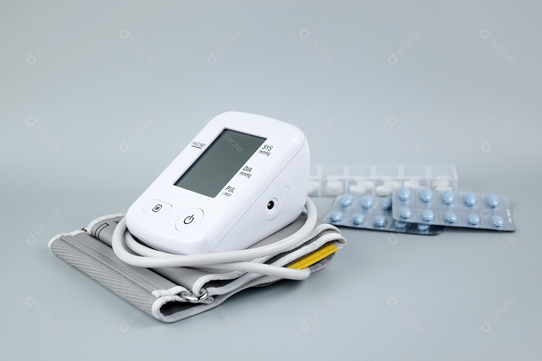 Aparelho digital de pressão arterial e pacote de comprimidos em um fundo claro