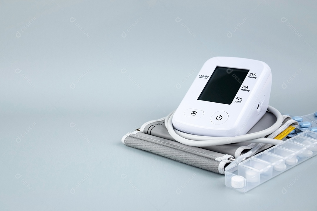 Aparelho digital de pressão arterial e pacote de comprimidos em um fundo claro