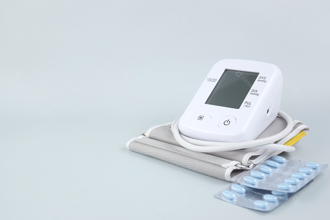 Aparelho digital de pressão arterial e pacote de comprimidos em um fundo claro