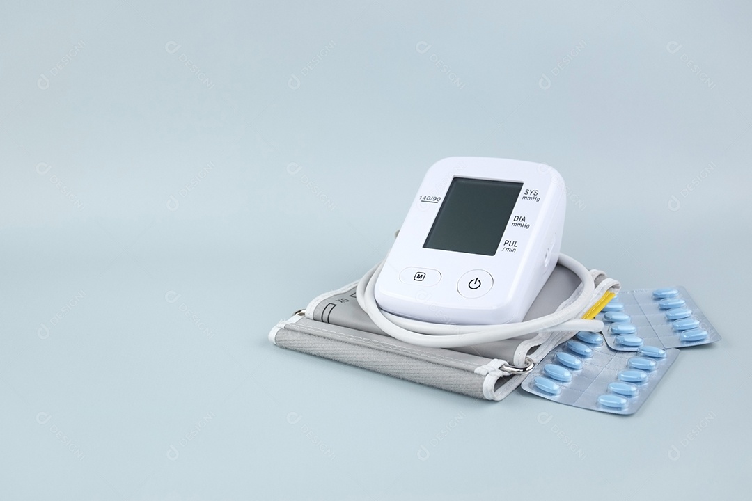 Aparelho digital de pressão arterial e pacote de comprimidos em um fundo claro