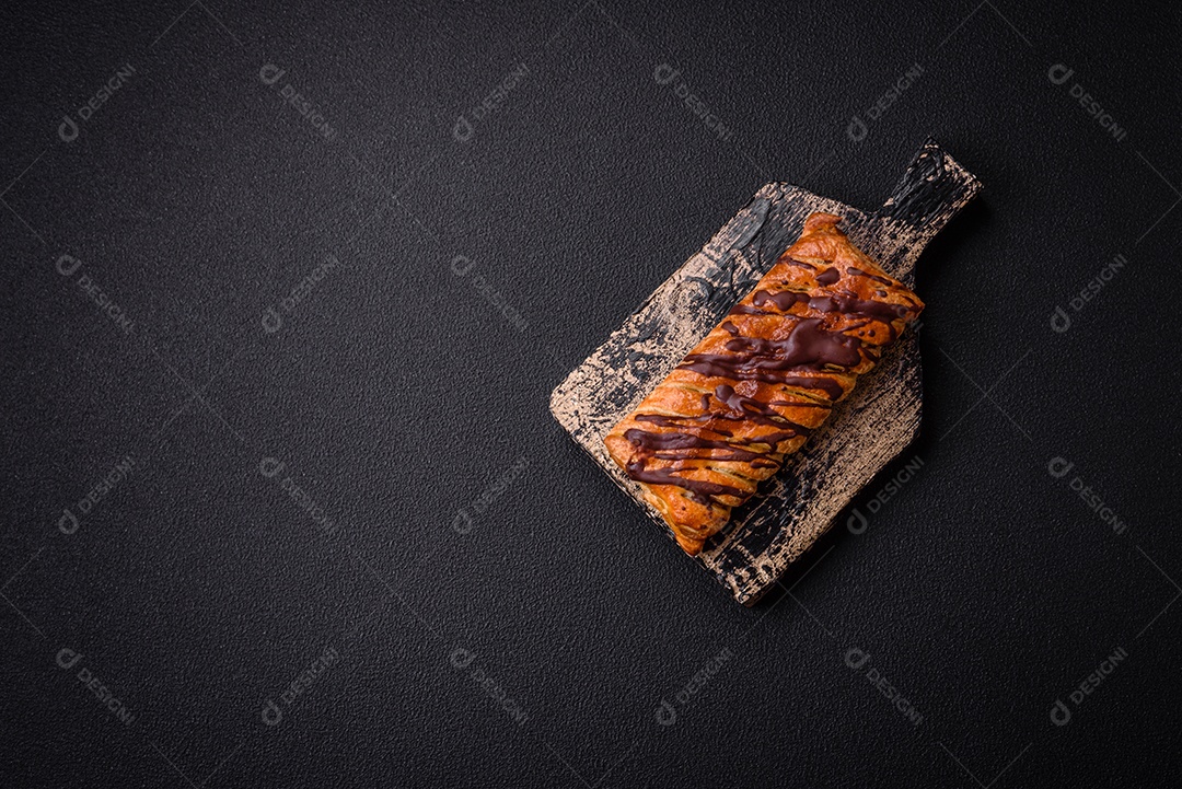 Deliciosa massa folhada crocante com chocolate e caramelo salgado sobre um fundo escuro de concreto