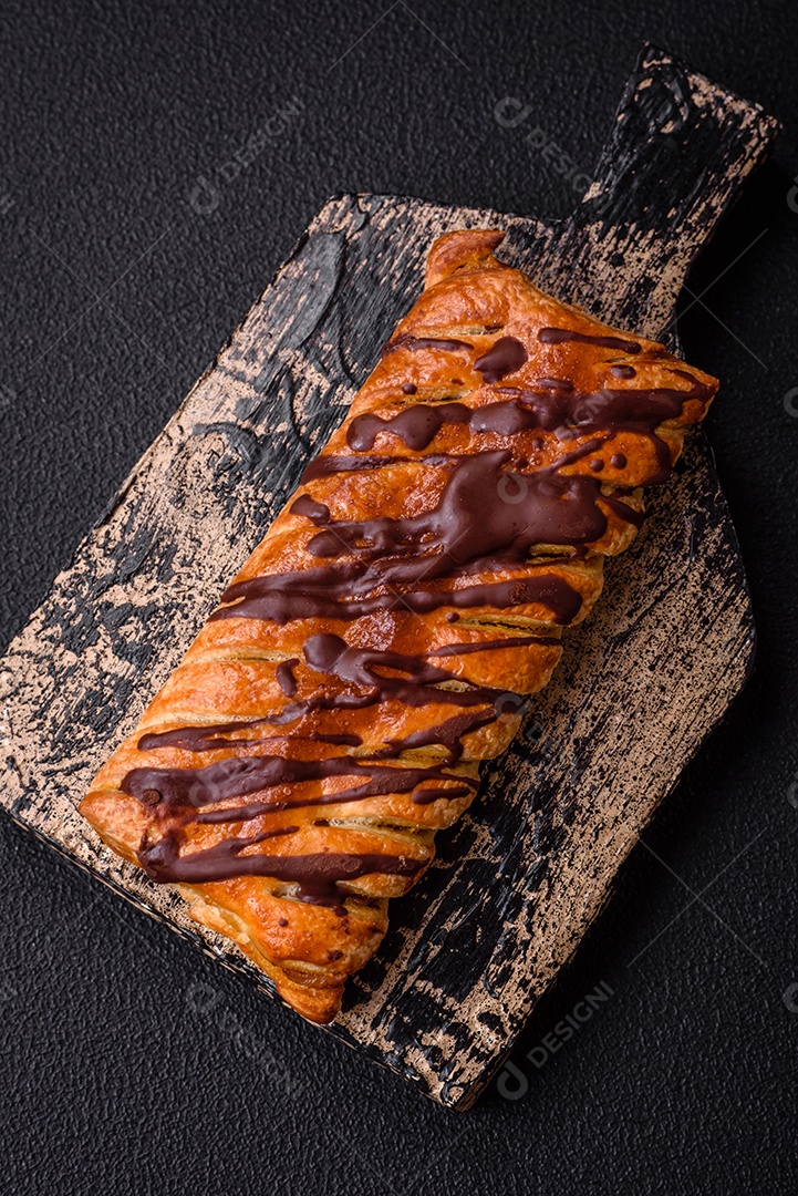 Deliciosa massa folhada crocante com chocolate e caramelo salgado sobre um fundo escuro de concreto