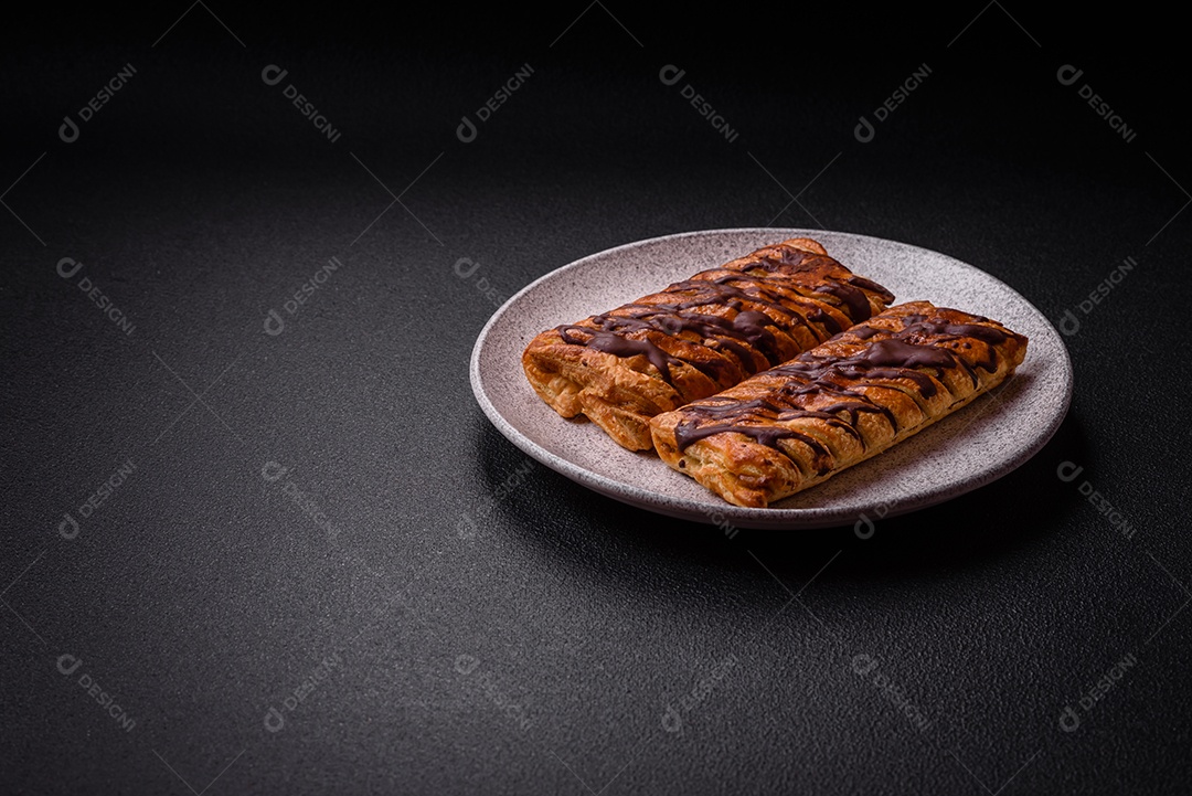 Deliciosa massa folhada crocante com chocolate e caramelo salgado sobre um fundo escuro de concreto