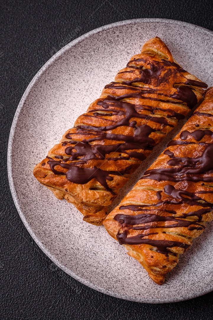 Deliciosa massa folhada crocante com chocolate e caramelo salgado sobre um fundo escuro de concreto
