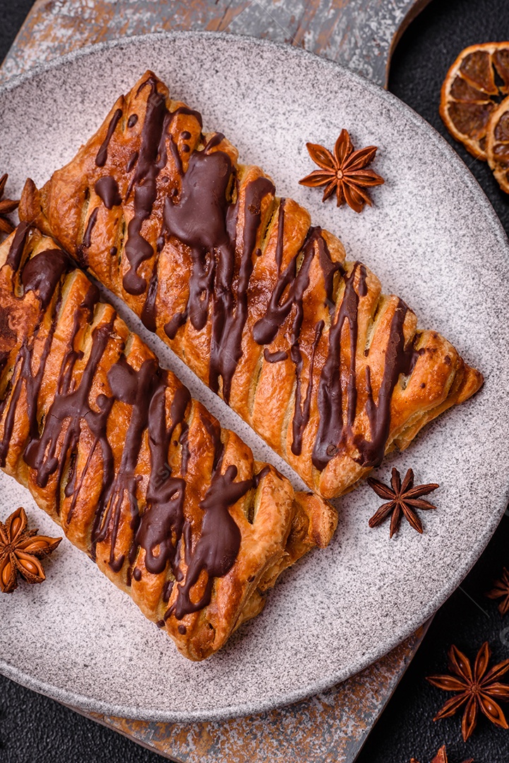 Deliciosa massa folhada crocante com chocolate e caramelo salgado sobre um fundo escuro de concreto