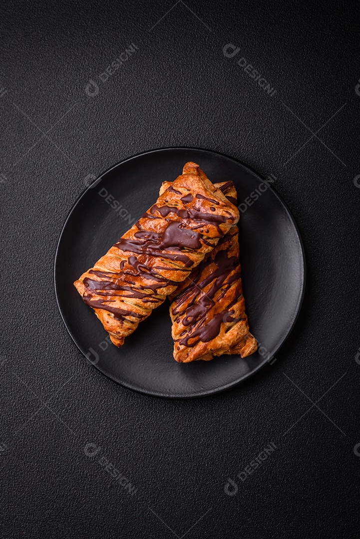 Deliciosa massa folhada crocante com chocolate e caramelo salgado sobre um fundo escuro de concreto