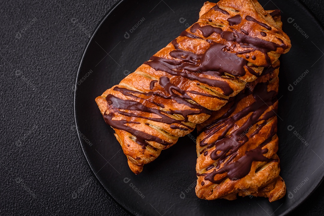 Deliciosa massa folhada crocante com chocolate e caramelo salgado sobre um fundo escuro de concreto