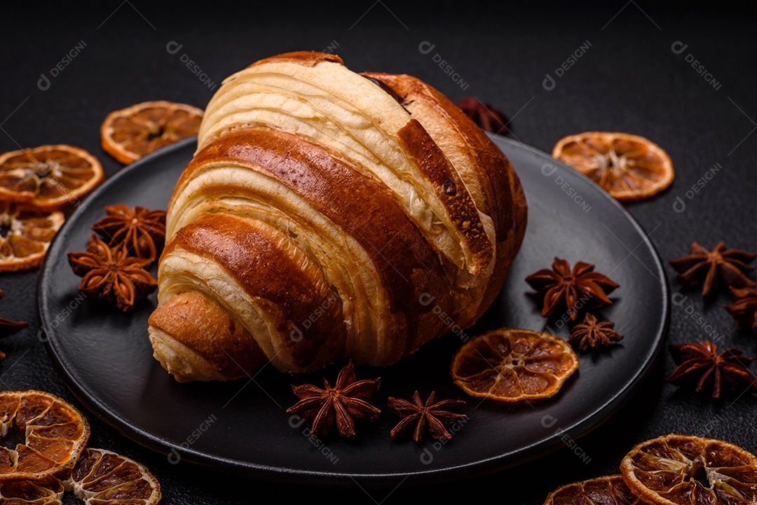 Deliciosa corneta de croissant doce e crocante com chocolate sobre um fundo escuro de concreto