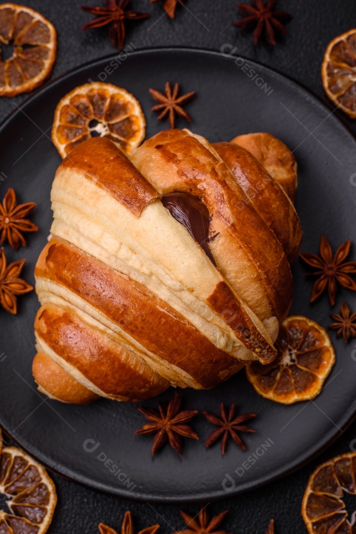 Deliciosa corneta de croissant doce e crocante com chocolate sobre um fundo escuro de concreto