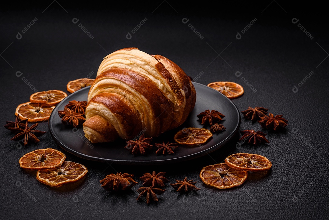 Deliciosa corneta de croissant doce e crocante com chocolate sobre um fundo escuro de concreto