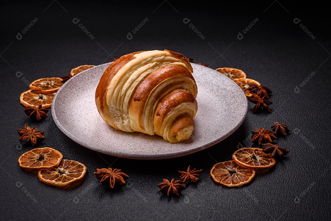 Deliciosa corneta de croissant doce e crocante com chocolate sobre um fundo escuro de concreto