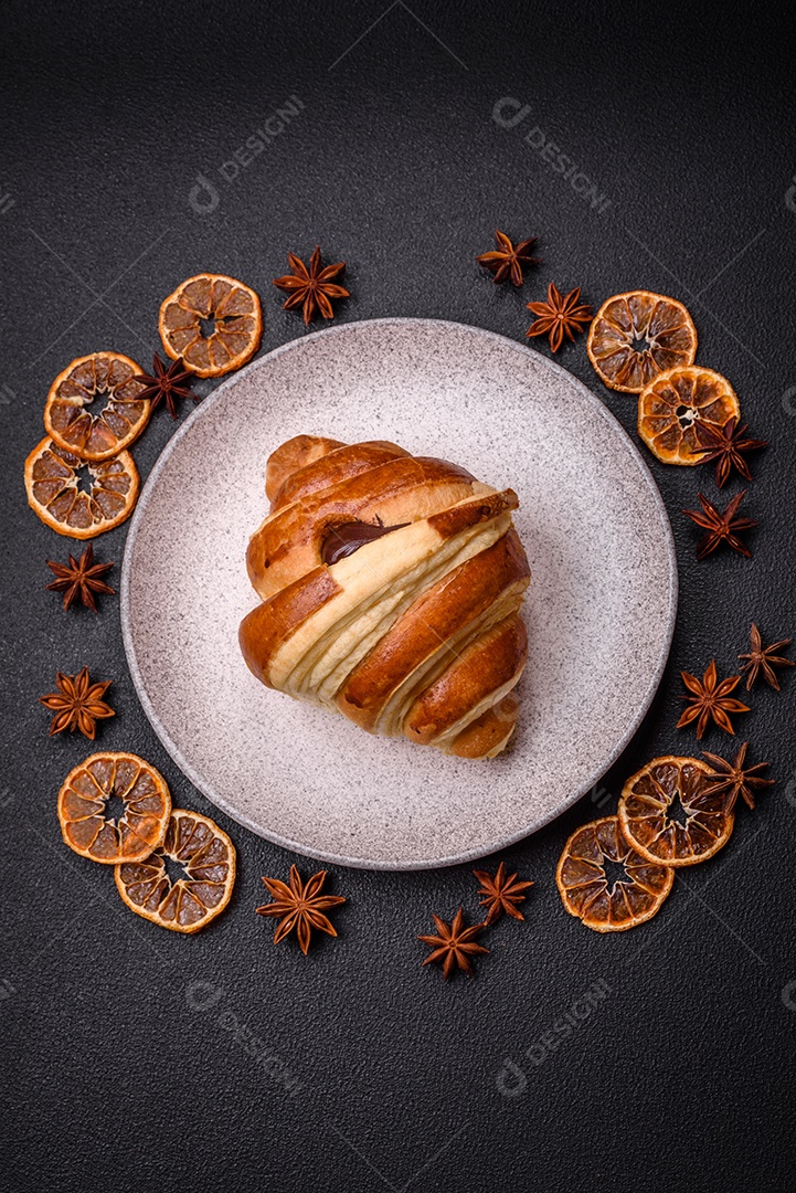 Deliciosa corneta de croissant doce e crocante com chocolate sobre um fundo escuro de concreto