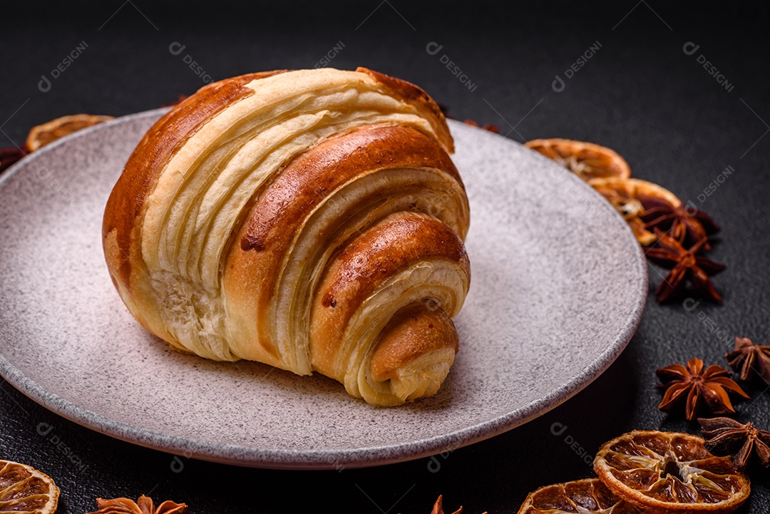Deliciosa corneta de croissant doce e crocante com chocolate sobre um fundo escuro de concreto