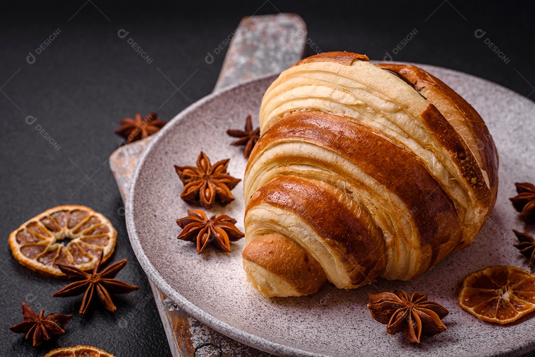 Deliciosa corneta de croissant doce e crocante com chocolate sobre um fundo escuro de concreto