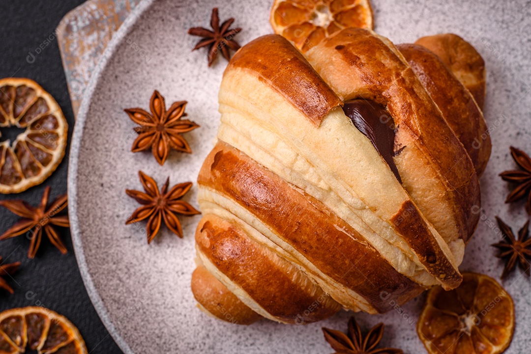 Deliciosa corneta de croissant doce e crocante com chocolate sobre um fundo escuro de concreto
