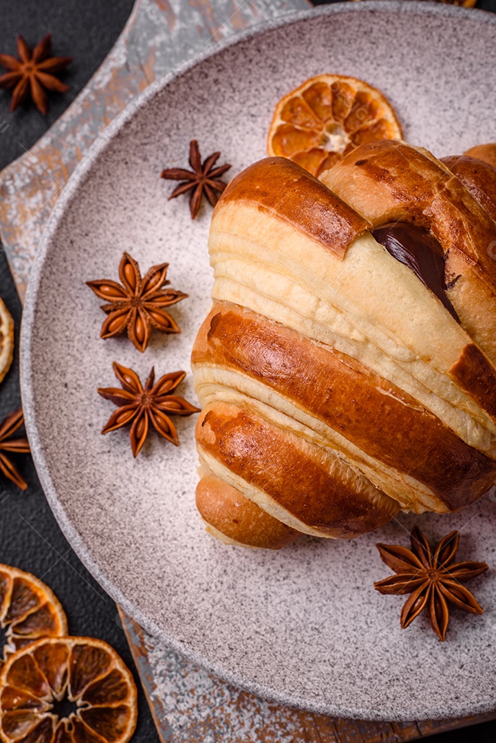 Deliciosa corneta de croissant doce e crocante com chocolate sobre um fundo escuro de concreto