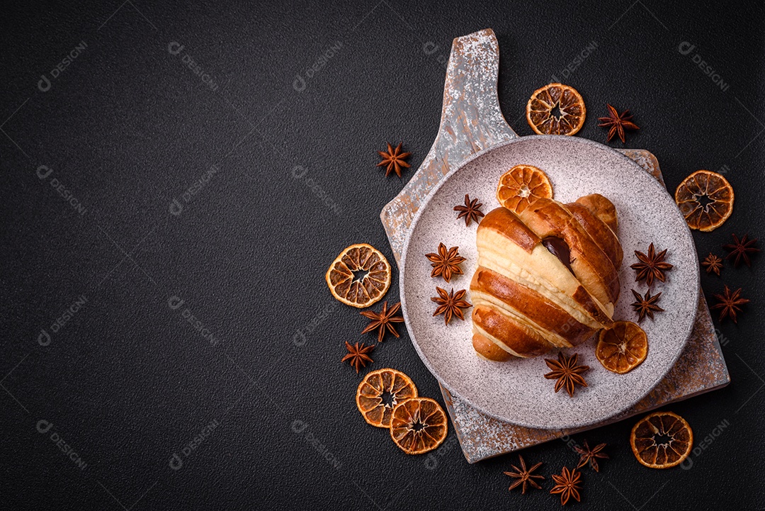 Deliciosa corneta de croissant doce e crocante com chocolate sobre um fundo escuro de concreto