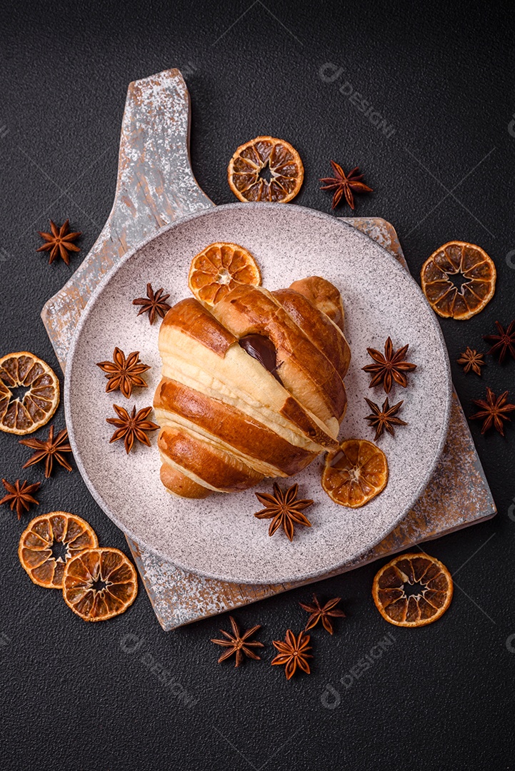 Deliciosa corneta de croissant doce e crocante com chocolate sobre um fundo escuro de concreto